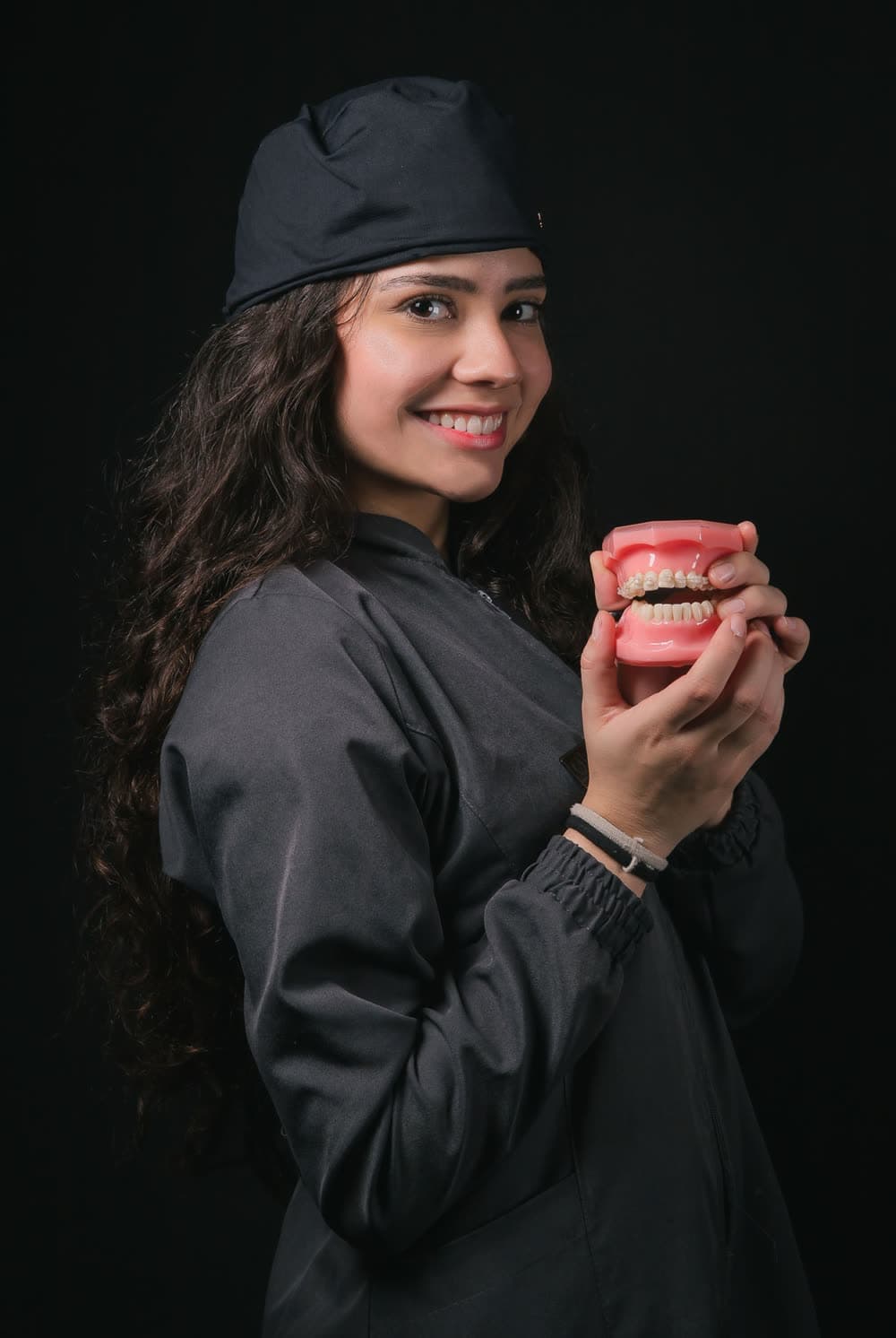 Dentista sorrindo, segurando um modelo de arcada dentária